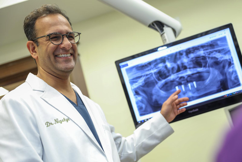 Dr. Sanil Nigalye Smiling While Presenting A Full Mouth Dental Implant Procedure To A Dental Patient