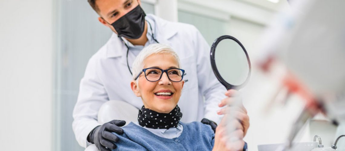 a dental assistant and patient happily looking at the patients new dental implant smile because their accurate placement won't lead to them getting peri-implantitis.
